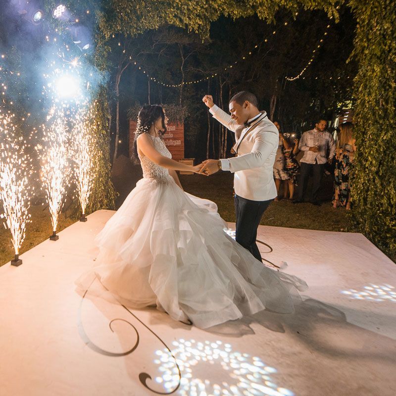 A bride and groom are dancing on a dance floor with fireworks in the background