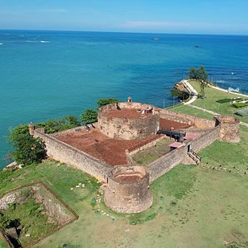 An aerial view of a castle on a hill overlooking the ocean.