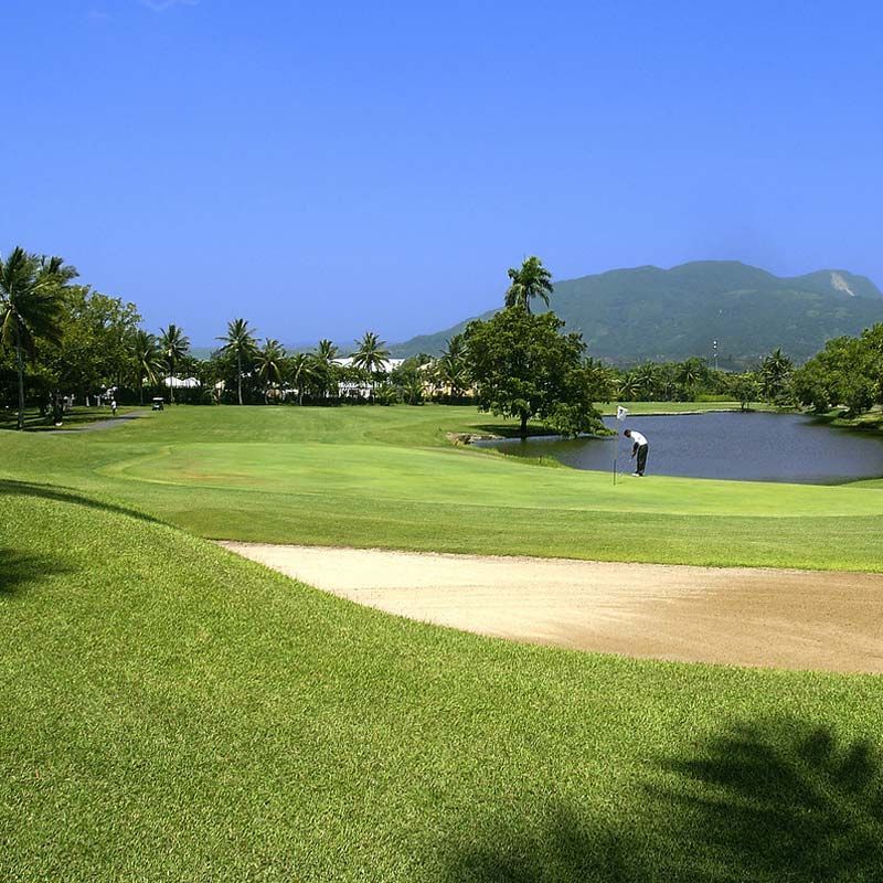 A golf course with a lake and mountains in the background