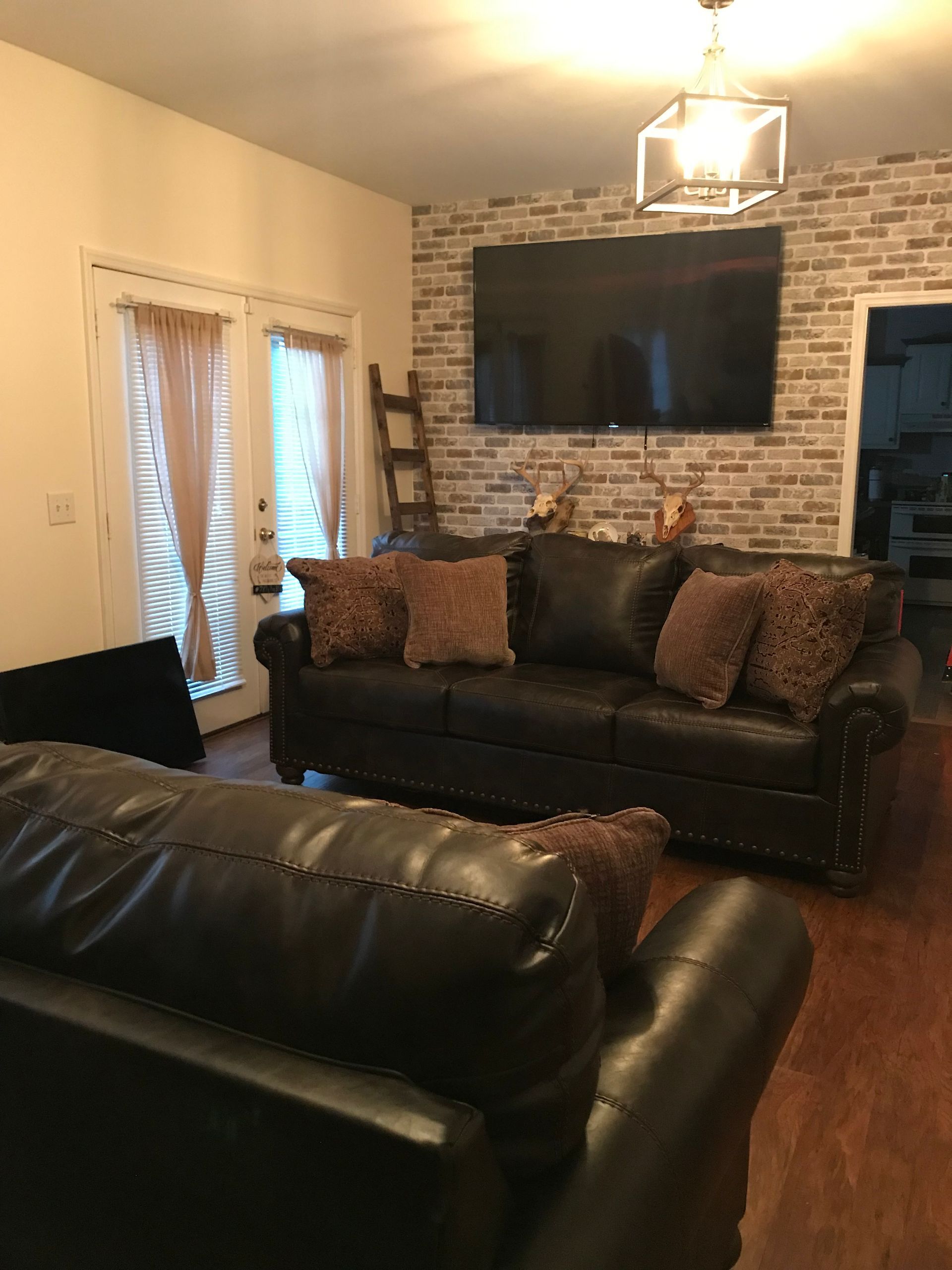 A living room with a black leather couch and a flat screen tv