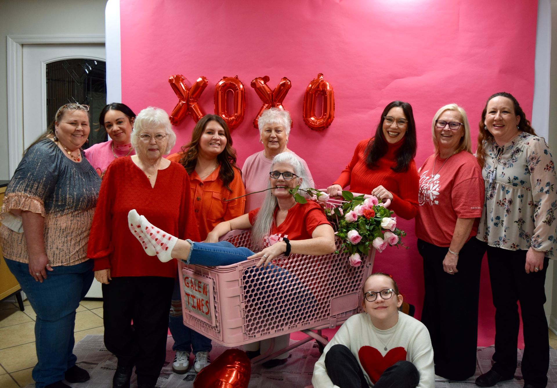 A group of nine people posing in front of a pink backdrop with
