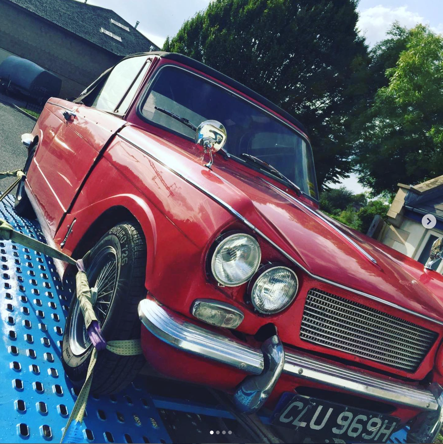 Red vintage Triumph car on a blue trailer, sunny day. License plate reads CLU 969H.