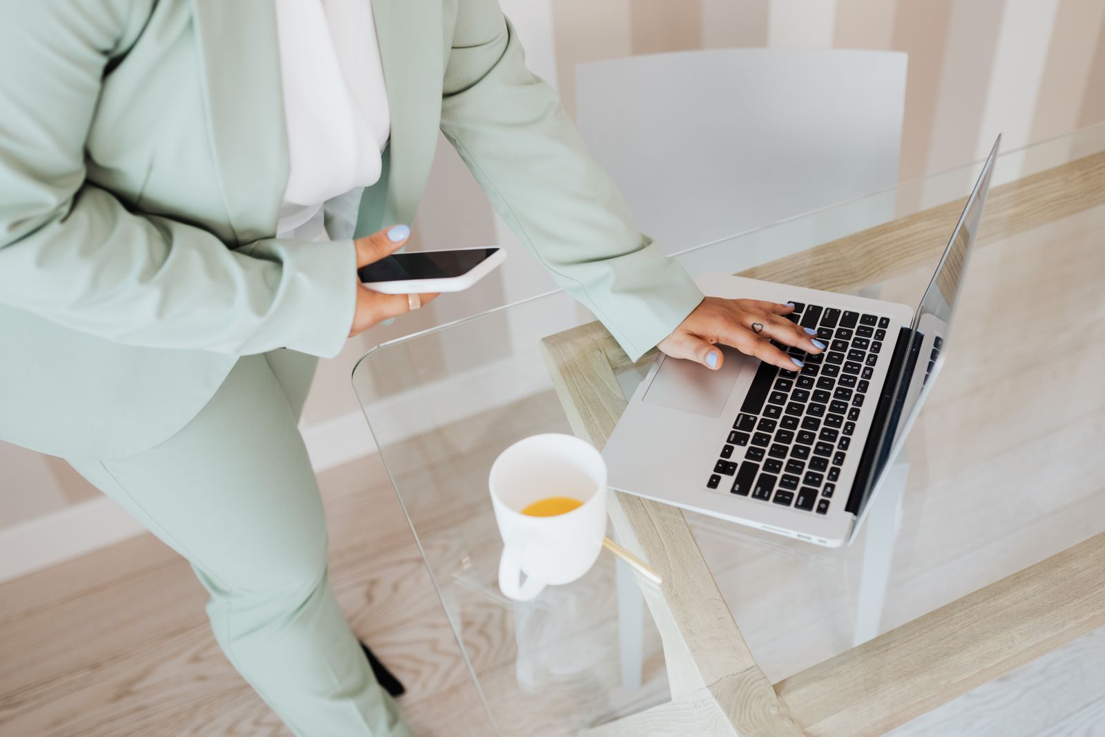 Professional working on a laptop and smartphone at a bright desk