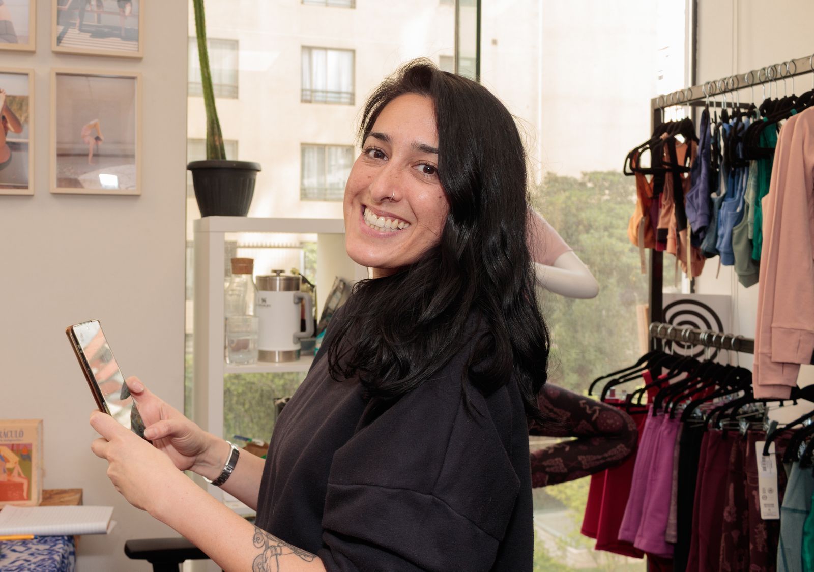 Smiling customer holding her smartphone inside a clothing store