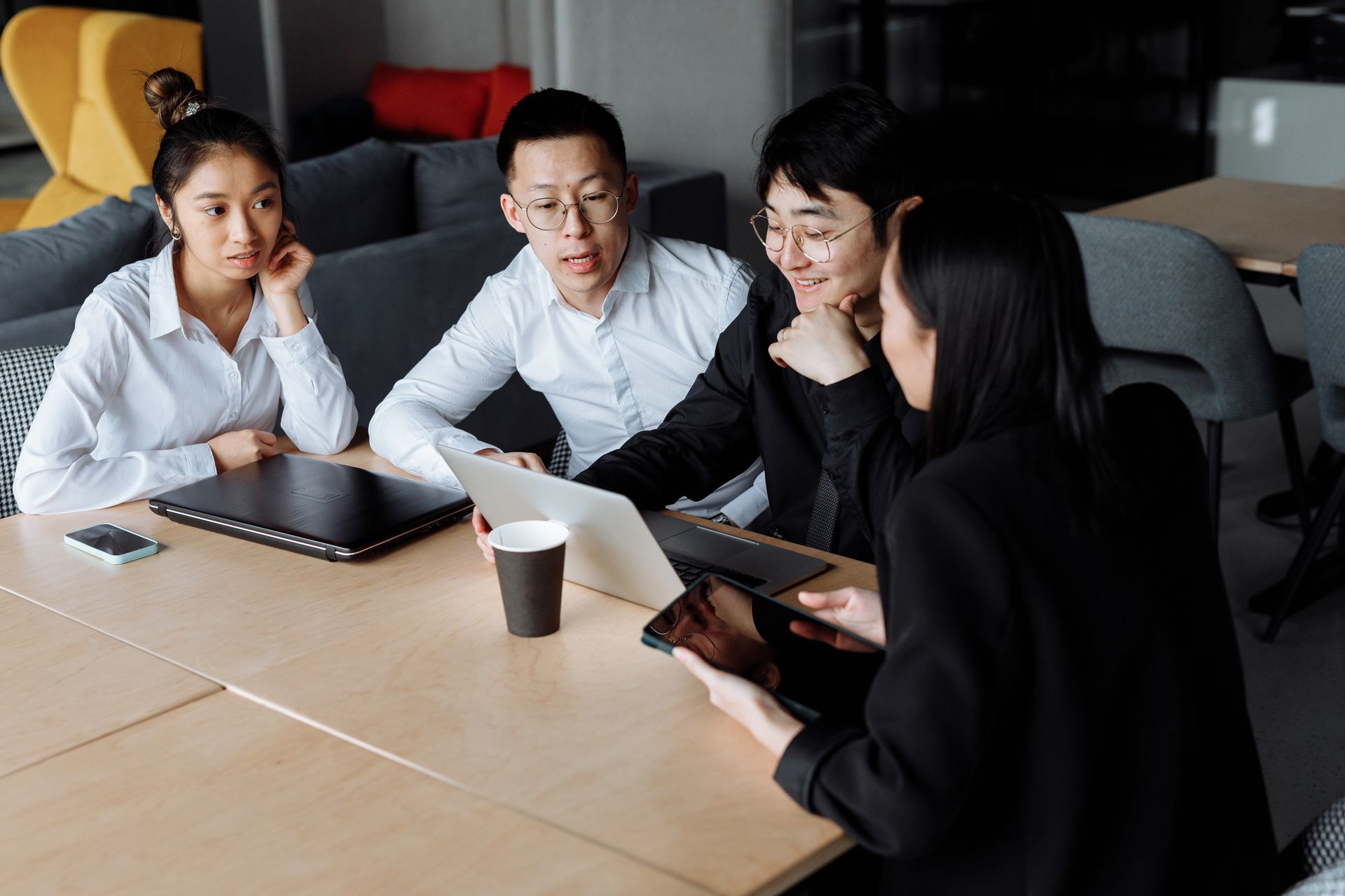 Small business team comparing software options around a laptop in a meeting