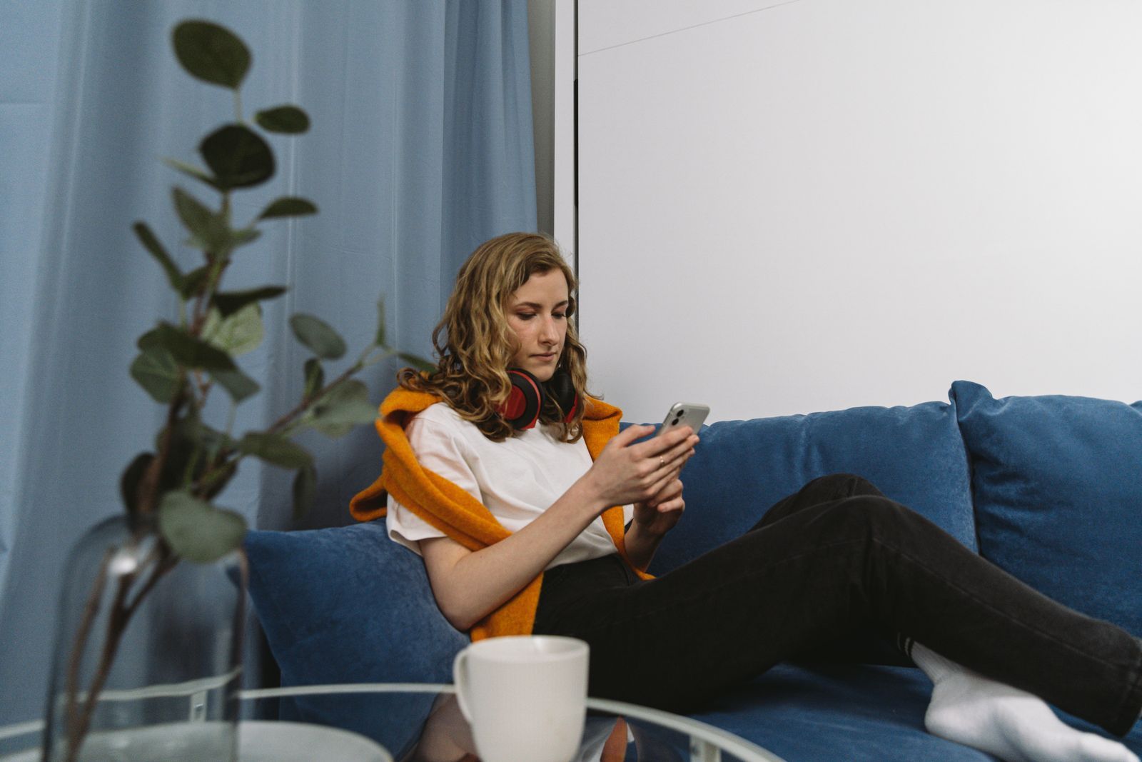 Woman relaxing on a sofa and browsing a website on her phone