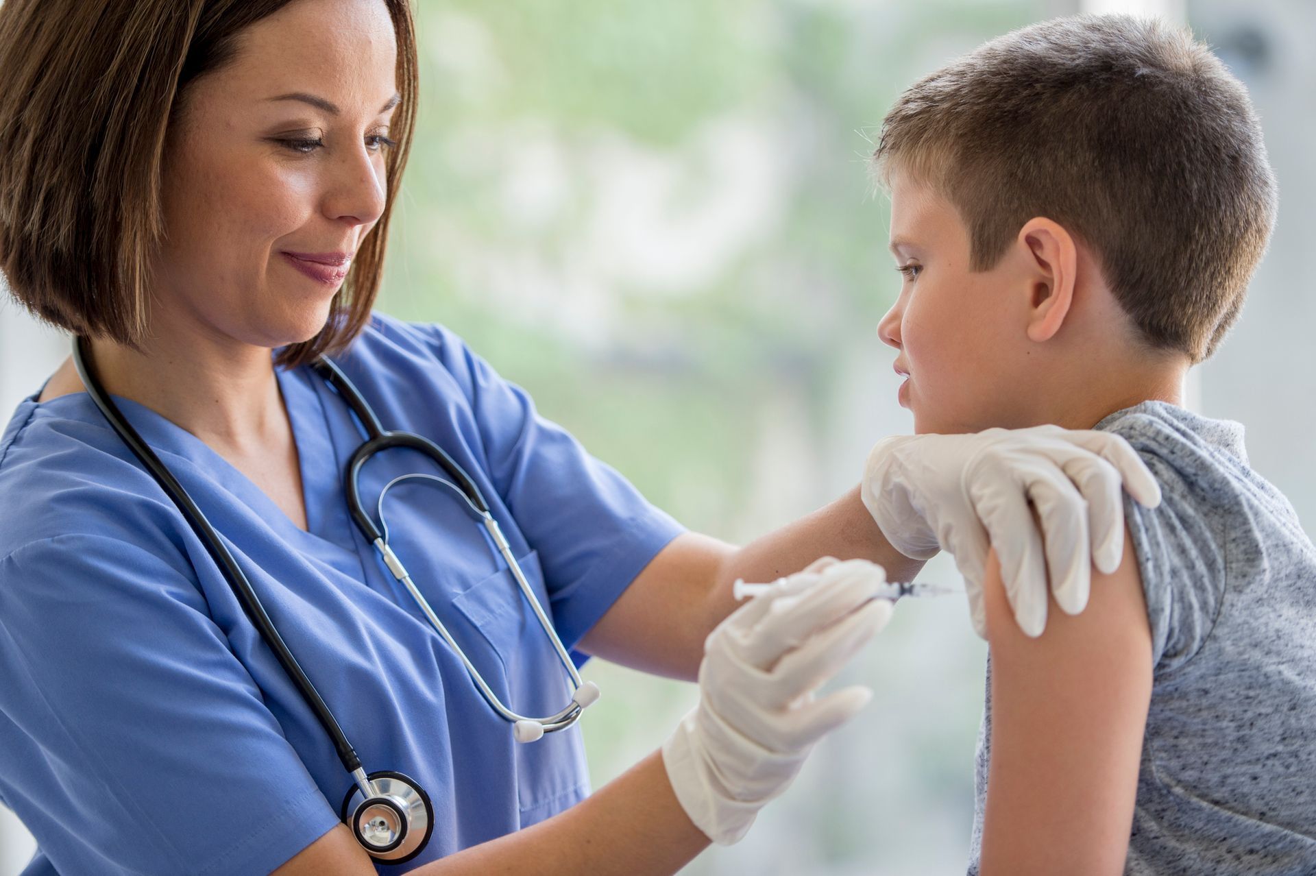 A nurse is giving a child an injection in his arm.