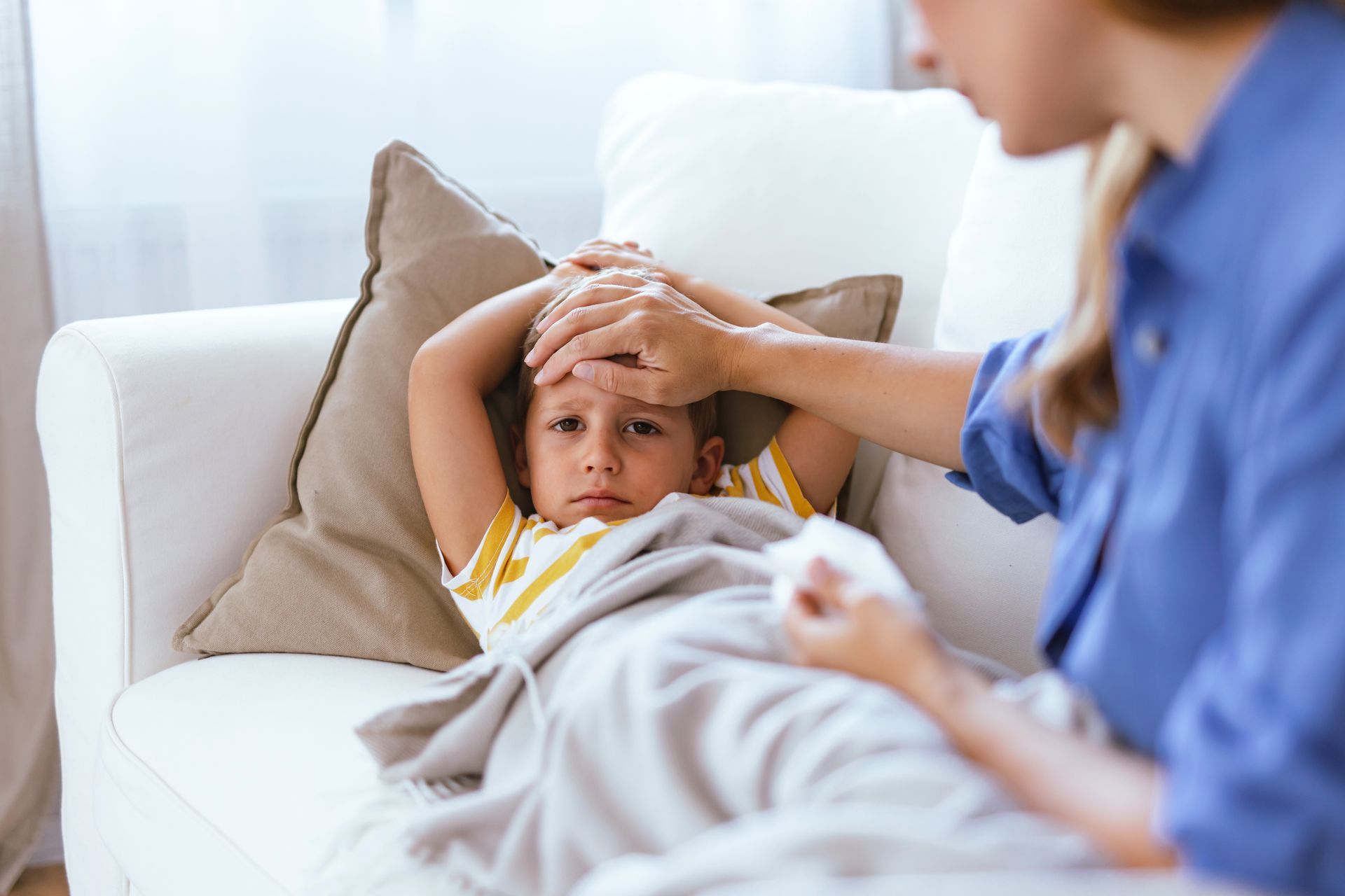 A woman is taking a child 's temperature on a couch.
