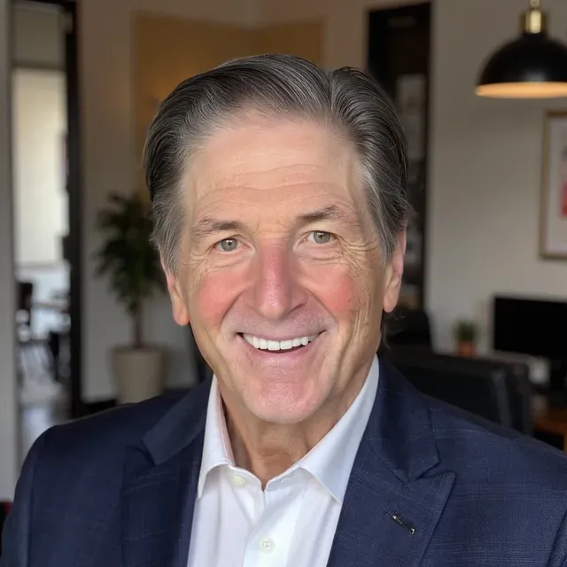 Smiling man in a gray suit and blue shirt on a city street, with blurred traffic behind him.