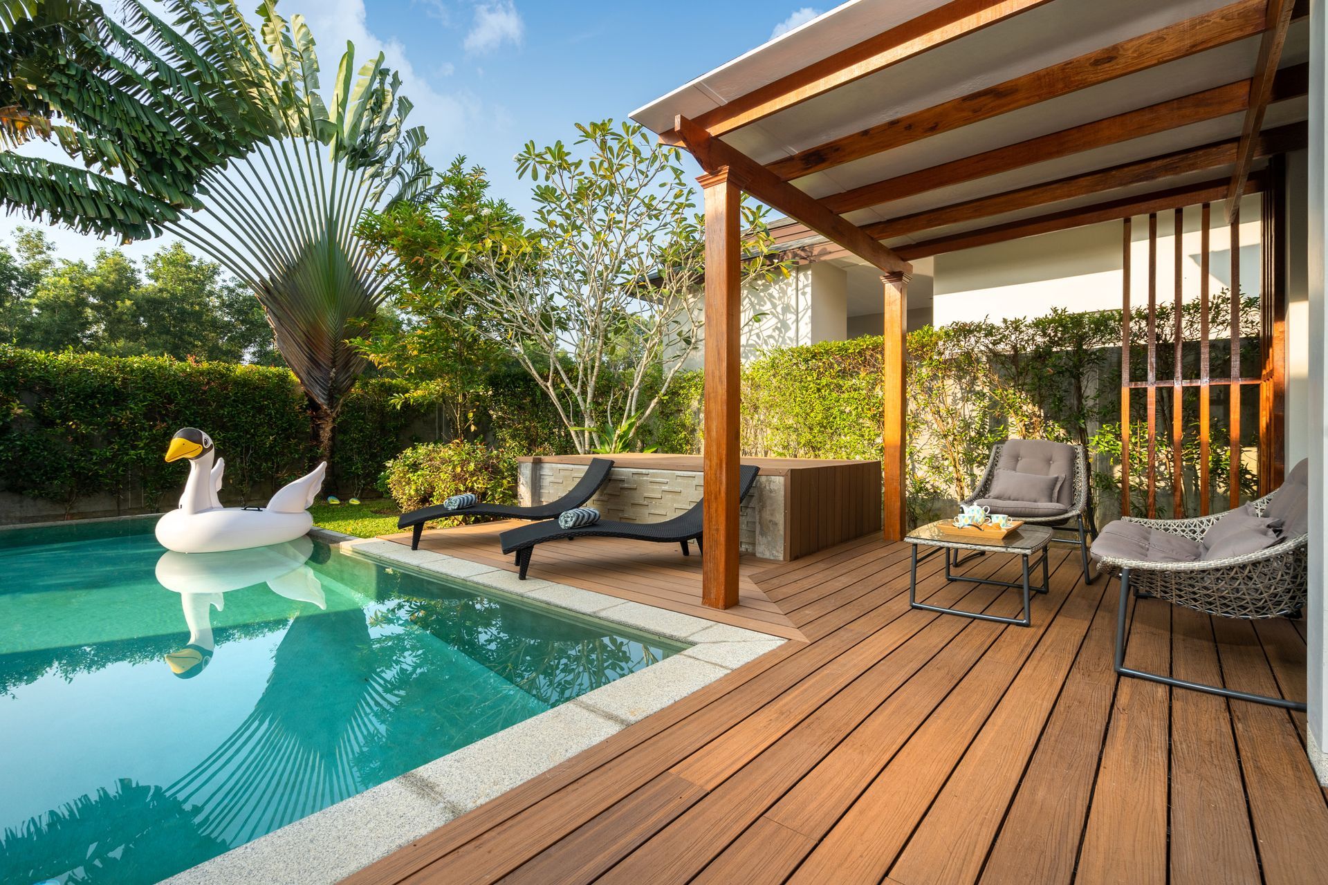 Une piscine avec un flotteur en forme de cygne et une terrasse en bois.