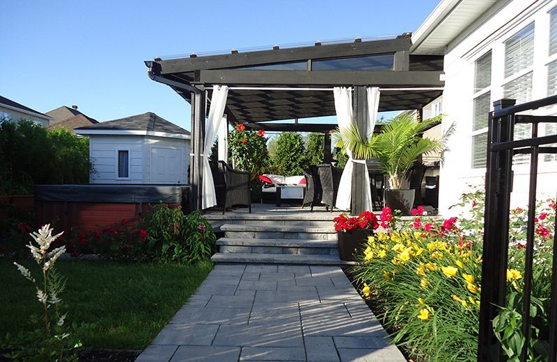Une passerelle menant à une maison avec une pergola et des fleurs