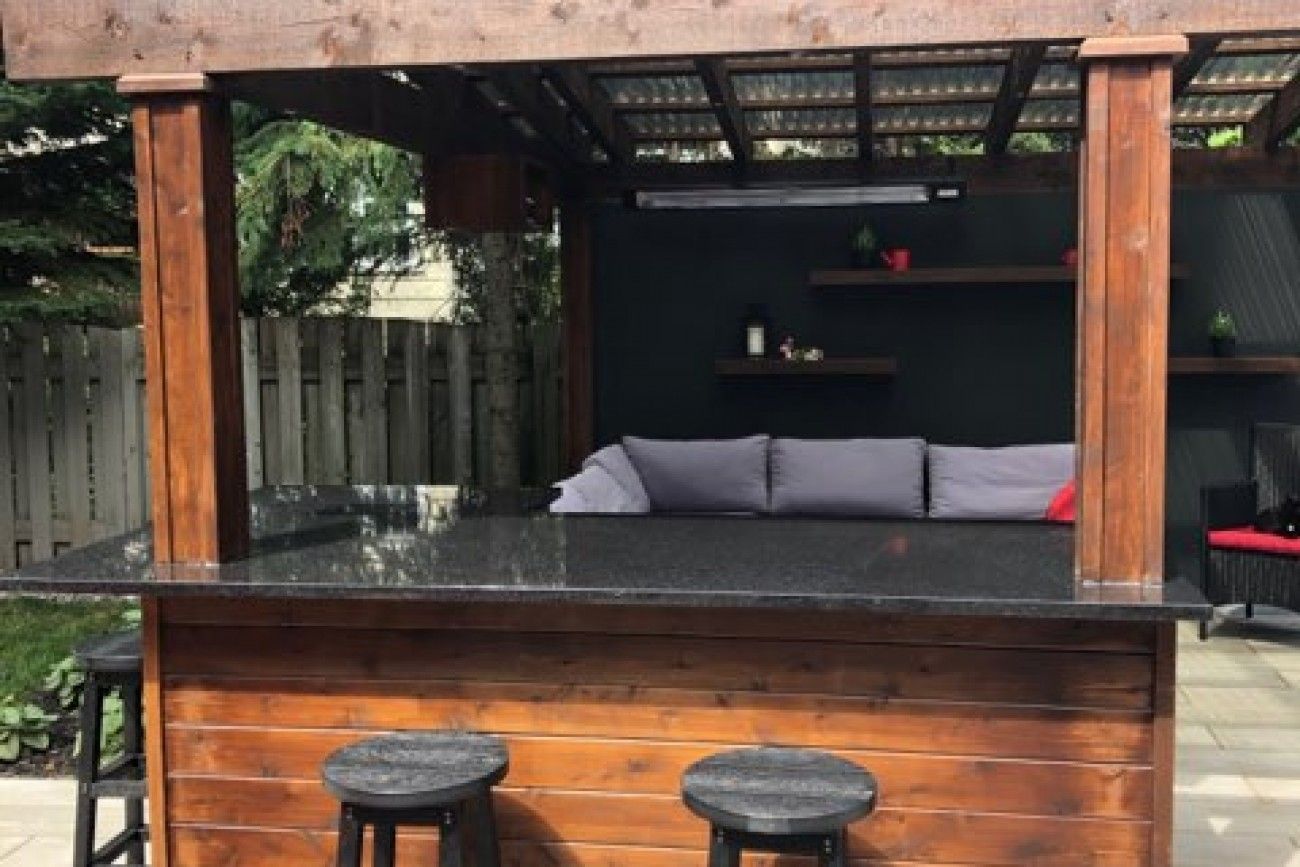 Un belvédère en bois avec un canapé et des tabourets en dessous.