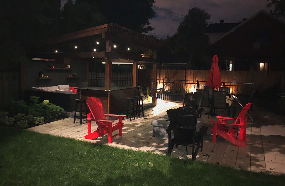 Une cour avec des chaises rouges et des parasols la nuit.