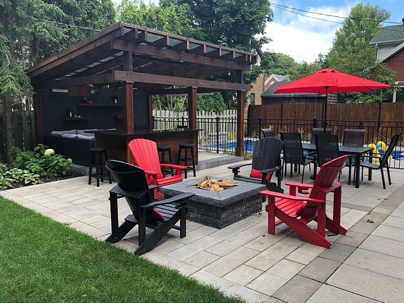 Une cour arrière avec un foyer, des chaises, des tables et des parasols.