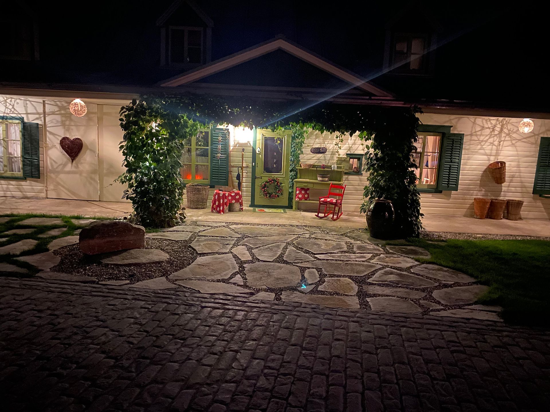 Une maison est éclairée la nuit avec une allée pavée devant elle.