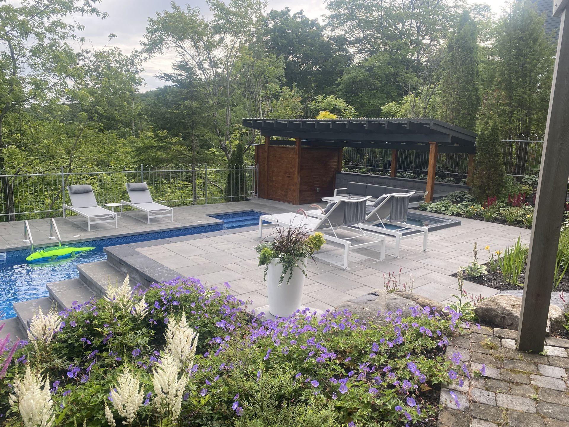 Une piscine entourée de fleurs et de chaises dans une cour arrière.