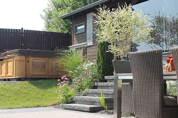 Une maison avec un jacuzzi dans l'arrière-cour et une table et des chaises devant.