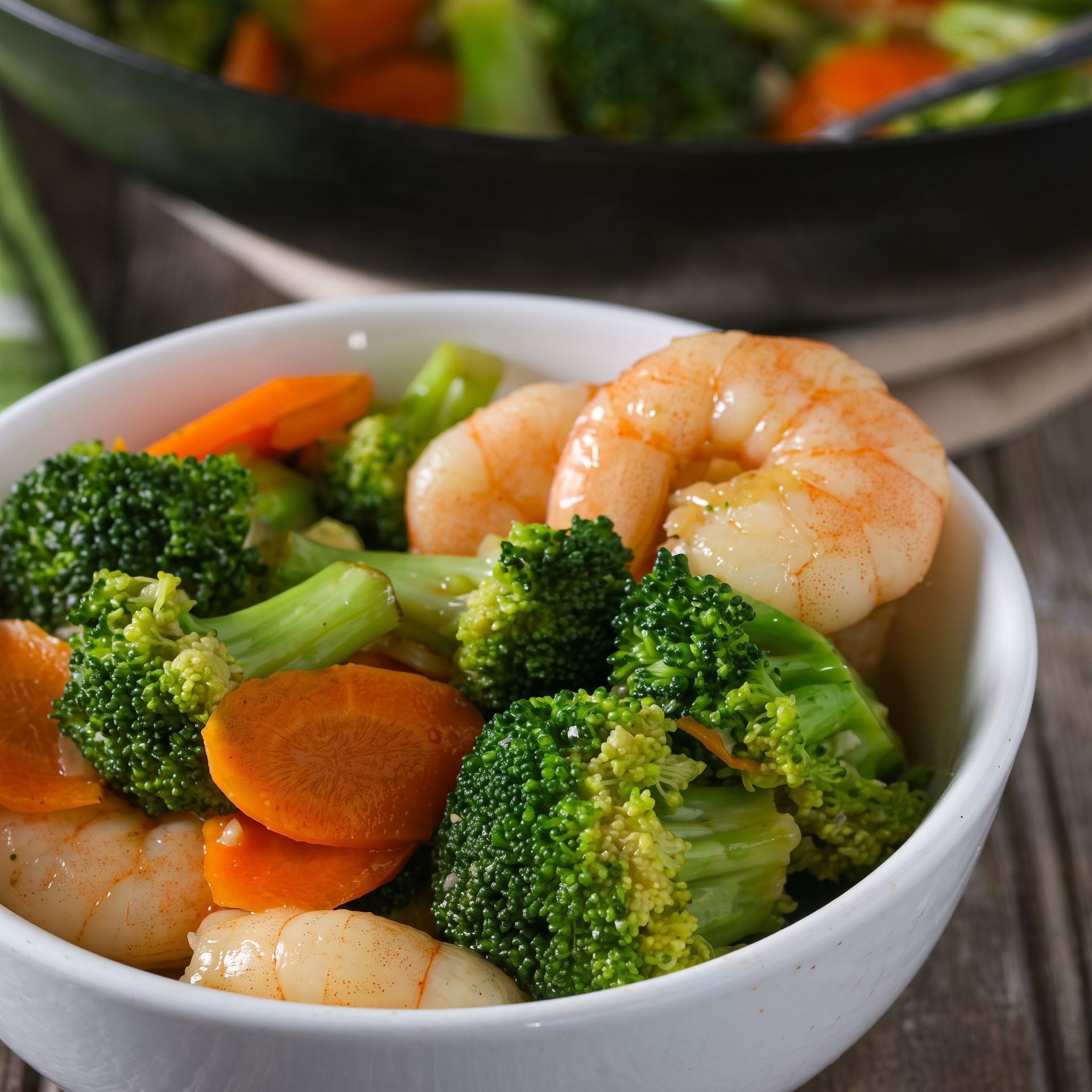 Shrimp and broccoli stir-fry with carrots in a white bowl
