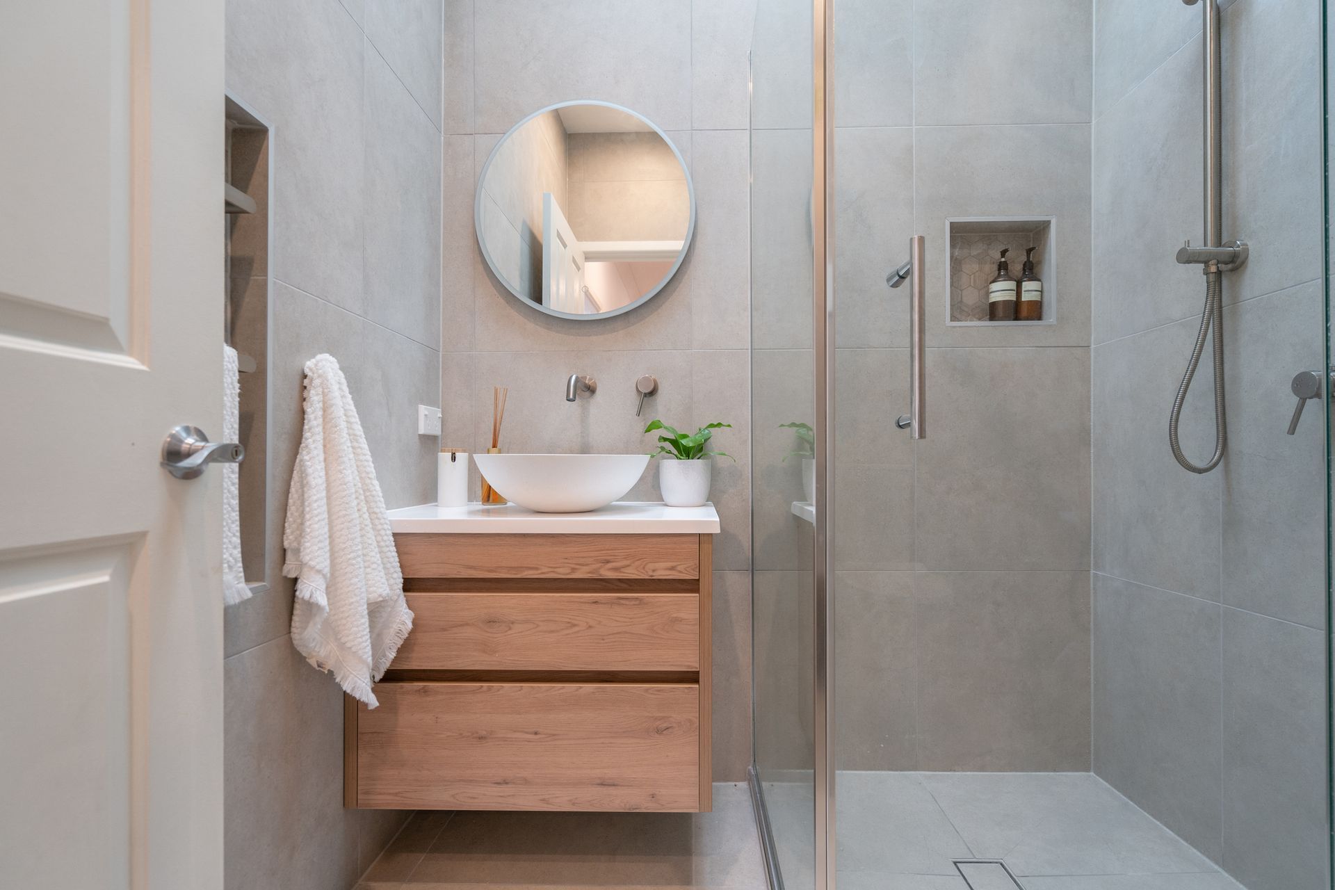 A bathroom with a sink , mirror , and walk in shower.