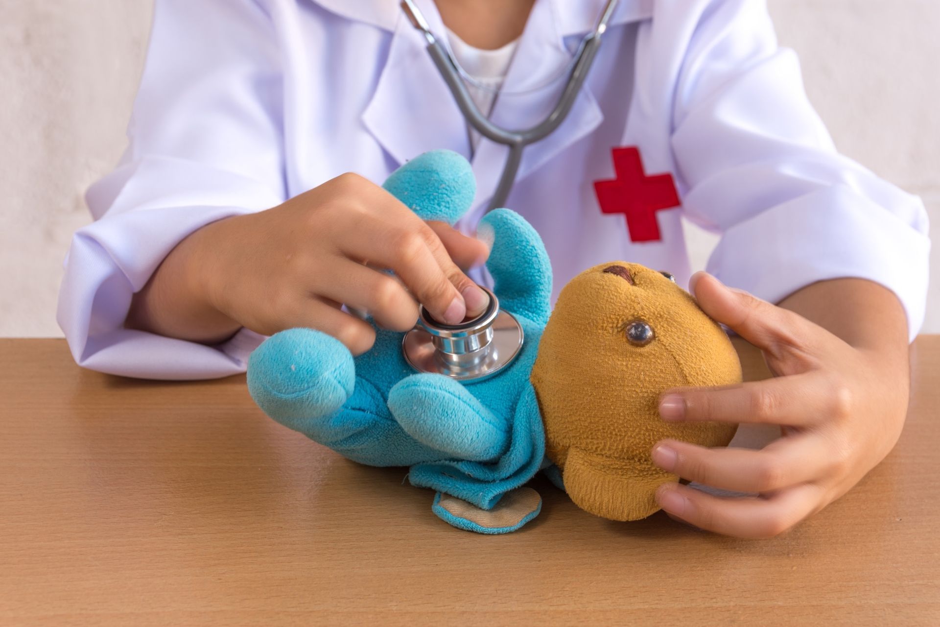 Image of a child playing doctor to a teddy bear