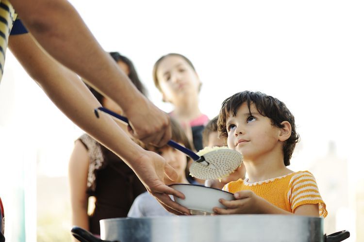 Image of a child being served from a community pot of food