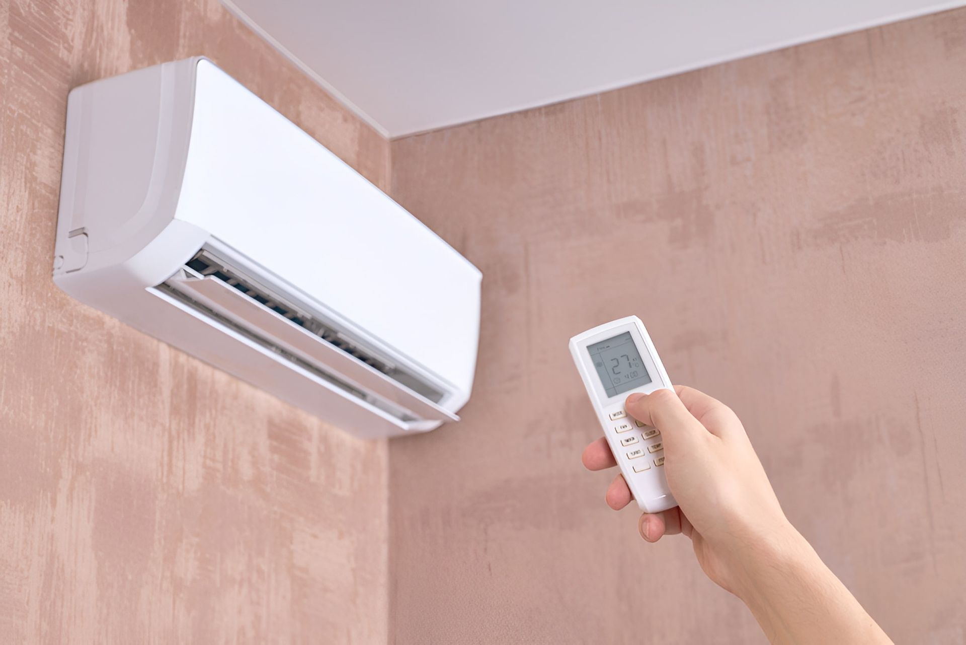 A Person Is Holding A Remote Control In Front Of An Air Conditioner — Beards Refrigeration & Air Conditioning in Mackay, QLD