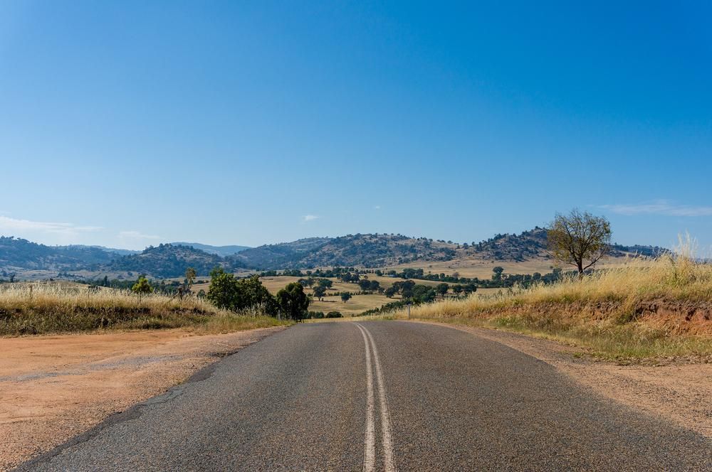 A Road Going Through A Desert Landscape With Mountains In The Background — Beards Refrigeration & Air Conditioning in Rural View, QLD