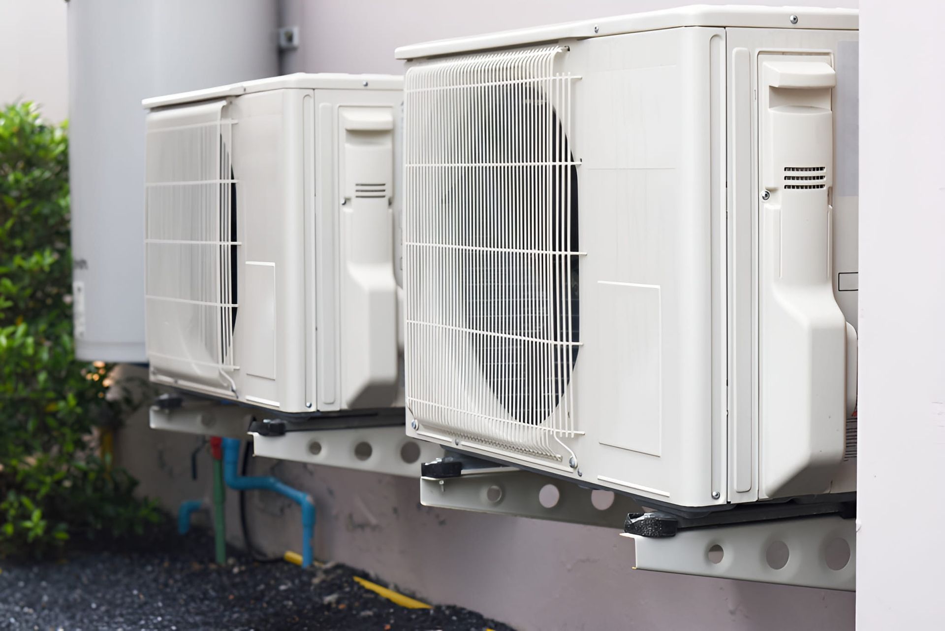 Two Air Conditioners Are Mounted On The Side Of A Building — Beards Refrigeration & Air Conditioning in Mackay, QLD