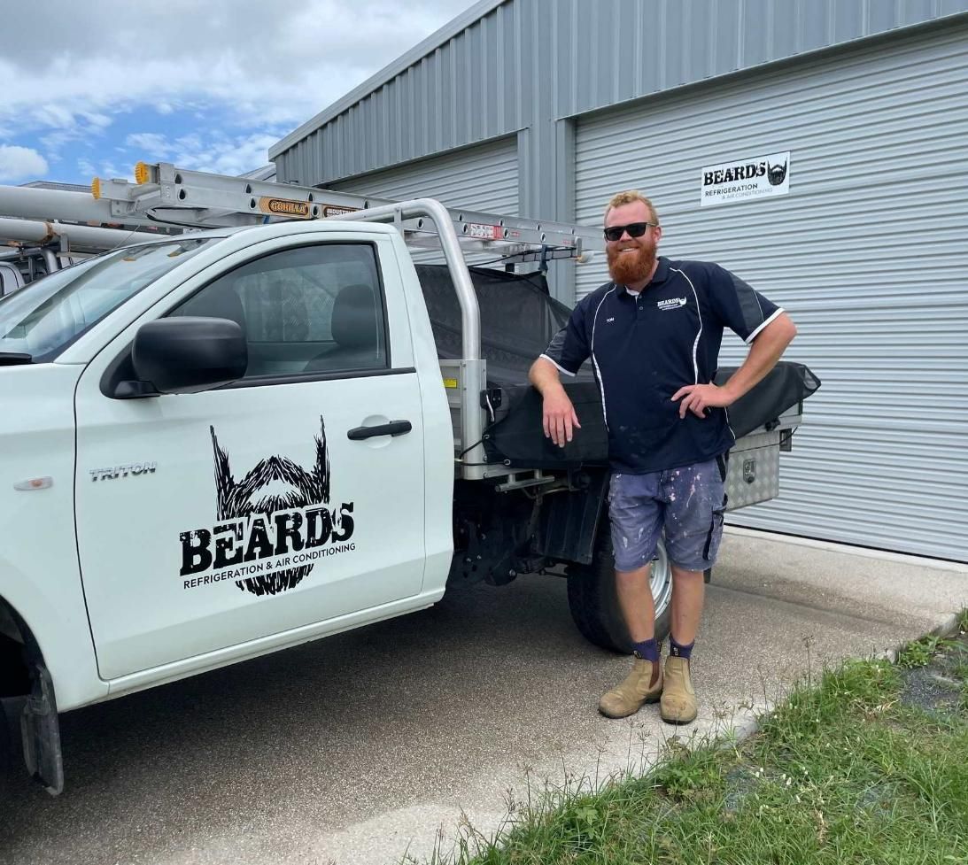 A Man With A Beard Is Standing Next To A White Truck — Beards Refrigeration & Air Conditioning in Mackay, QLD