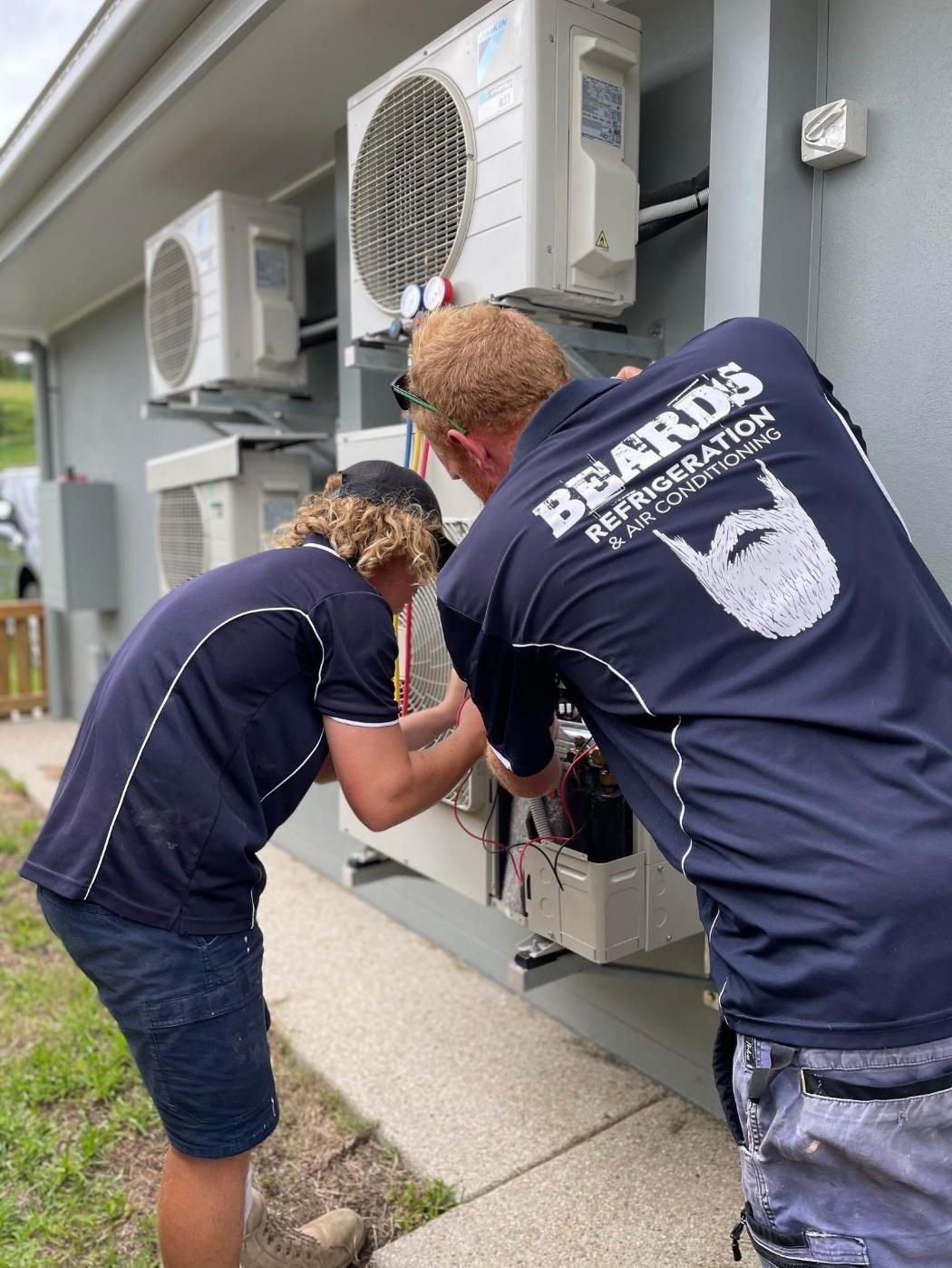 Two Men Are Working On An Air Conditioner Outside Of A Building — Beards Refrigeration & Air Conditioning in Rural View, QLD