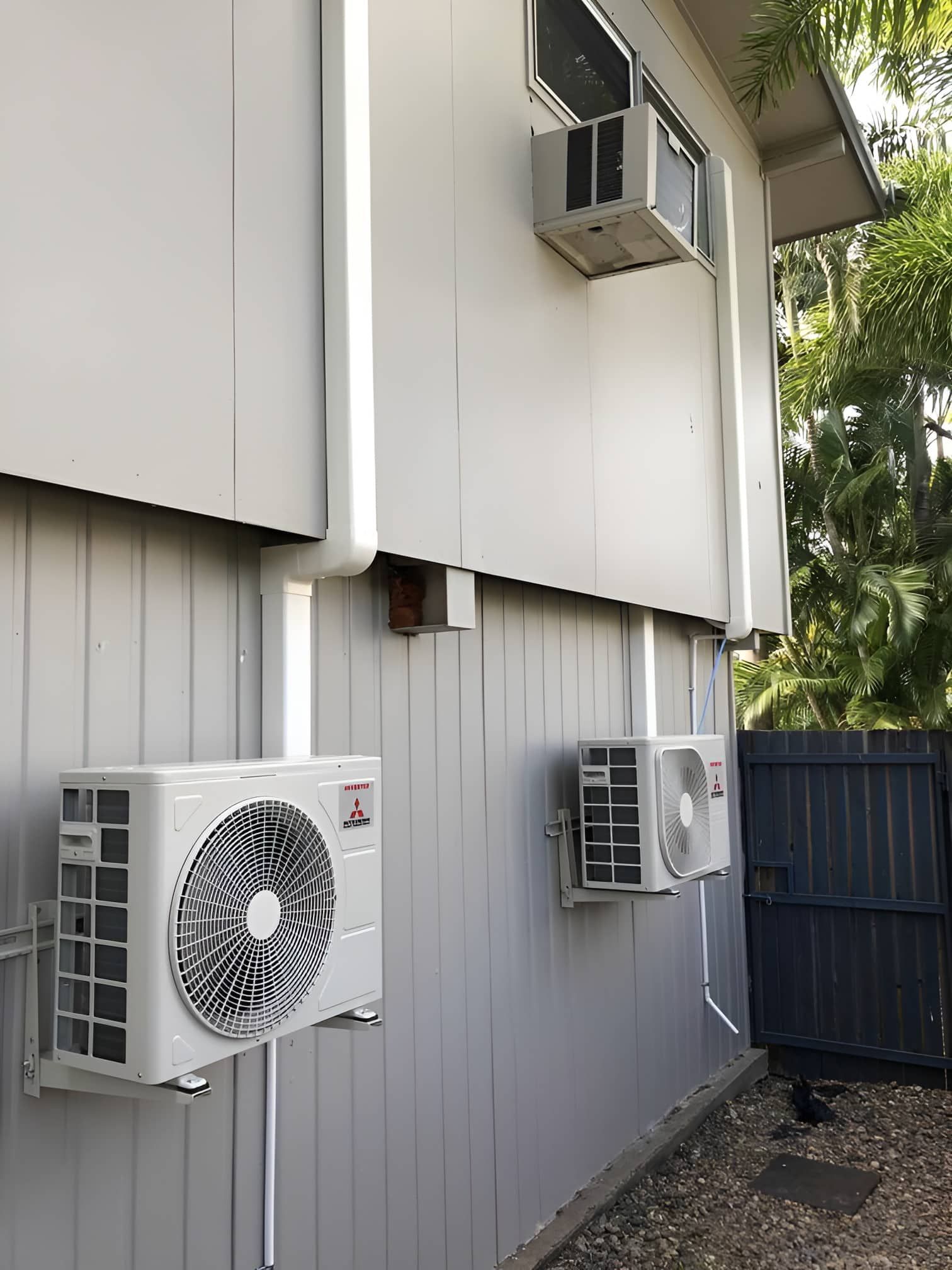 Two Air Conditioners Are Mounted On The Side Of A Building — Beards Refrigeration & Air Conditioning in Bucasia, QLD