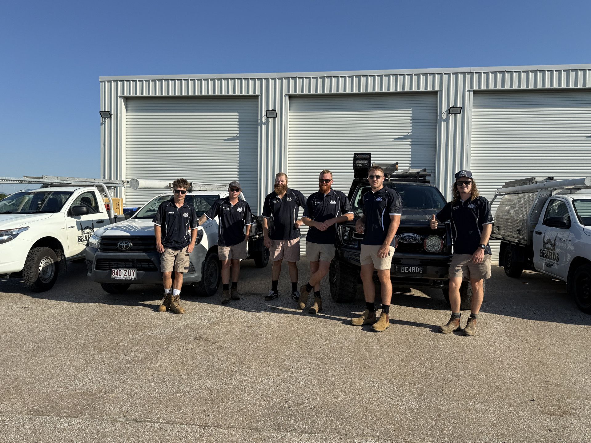 A Group Of Men In Uniform Standing By Some Vehicles — Beards Refrigeration & Air Conditioning in Bucasia, QLD