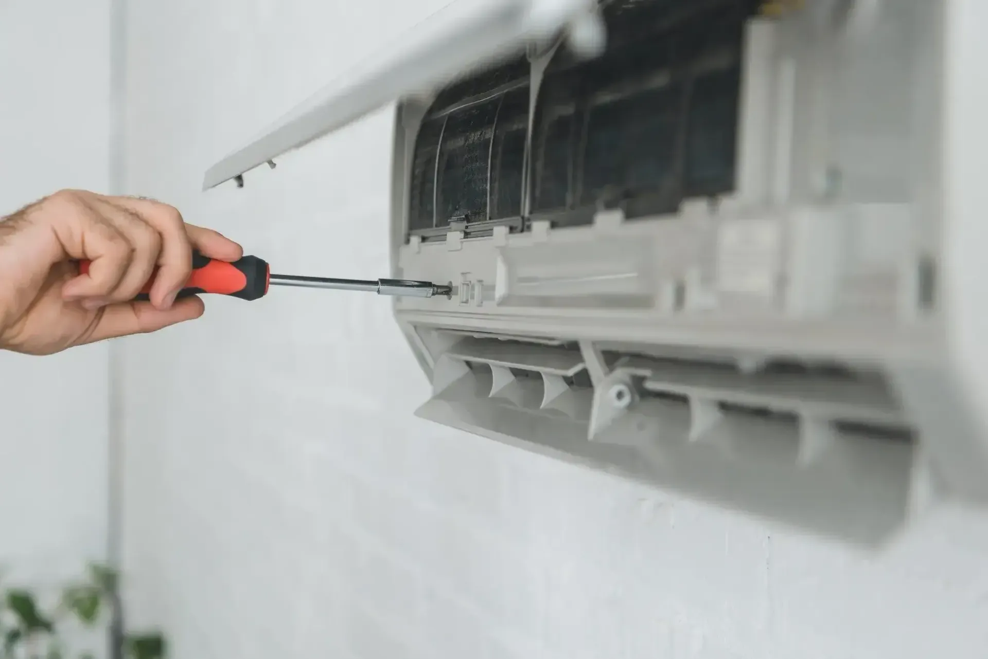 A Person Is Fixing An Air Conditioner With A Screwdriver — Beards Refrigeration & Air Conditioning in Mackay, QLD