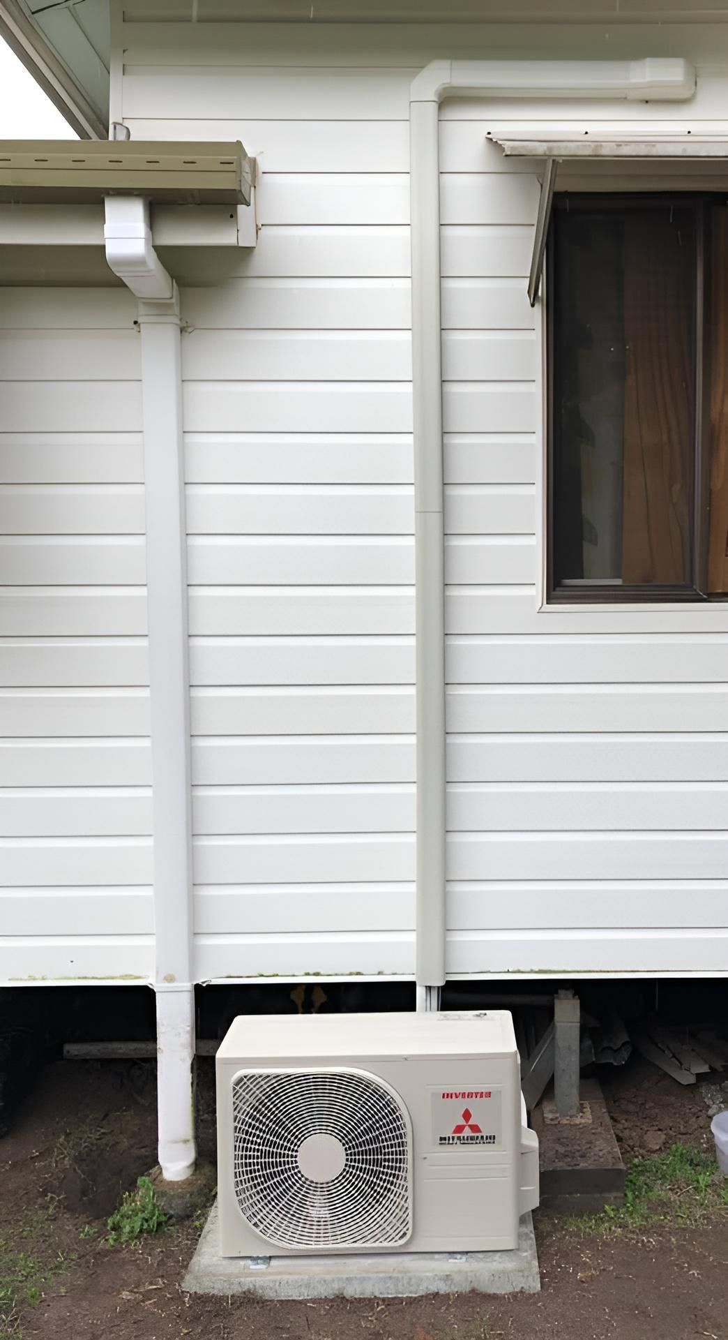 A White House With A Fan On The Side Of It — Beards Refrigeration & Air Conditioning in Bucasia, QLD