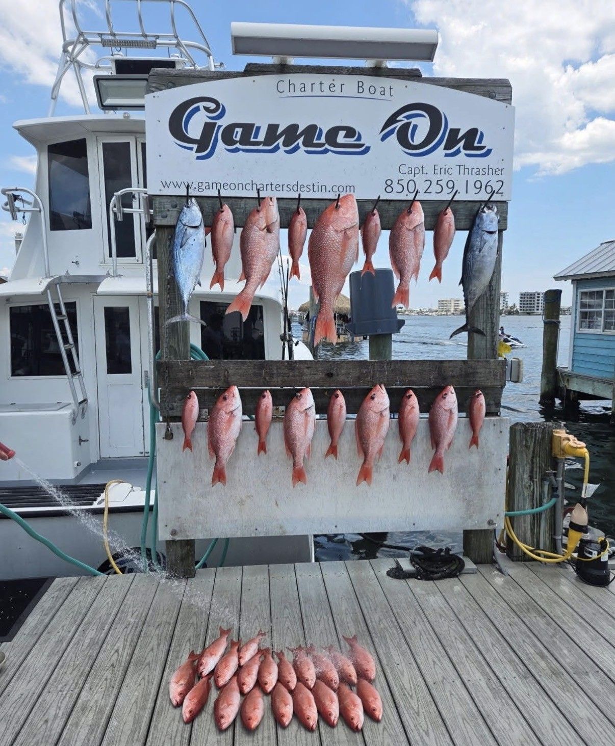 Fishing boat stern with racks of red snapper and a small pile of fish on the dock