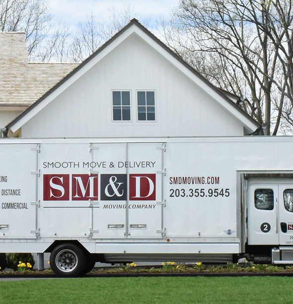 White moving truck in front of a white house with a gabled roof.