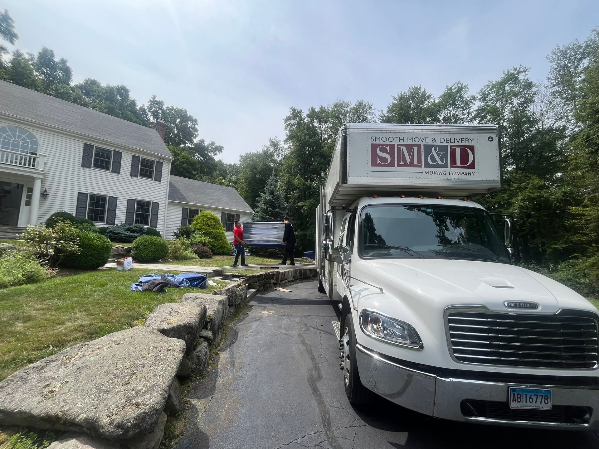 Smooth Move & Delivery truck parked at a residential home for a local house move, showing the SM&D company logo.