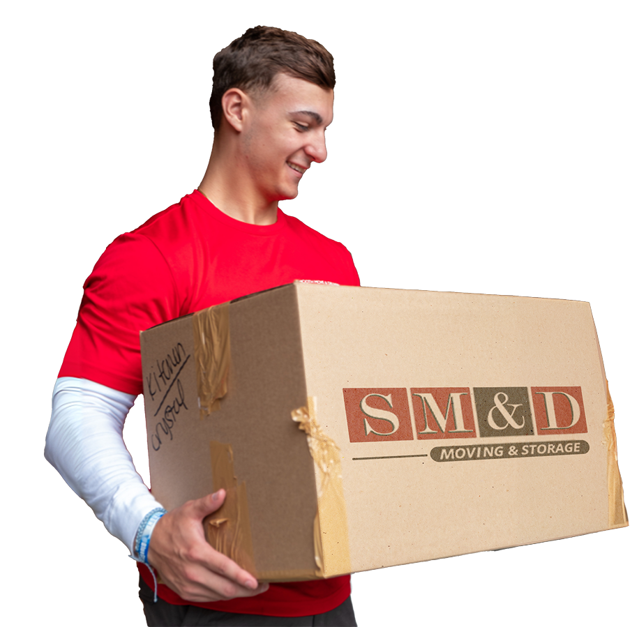 A person in red shirt smiles, holding a cardboard box with