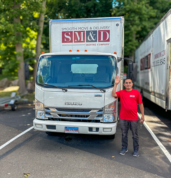 Man waves in front of a white moving truck labeled