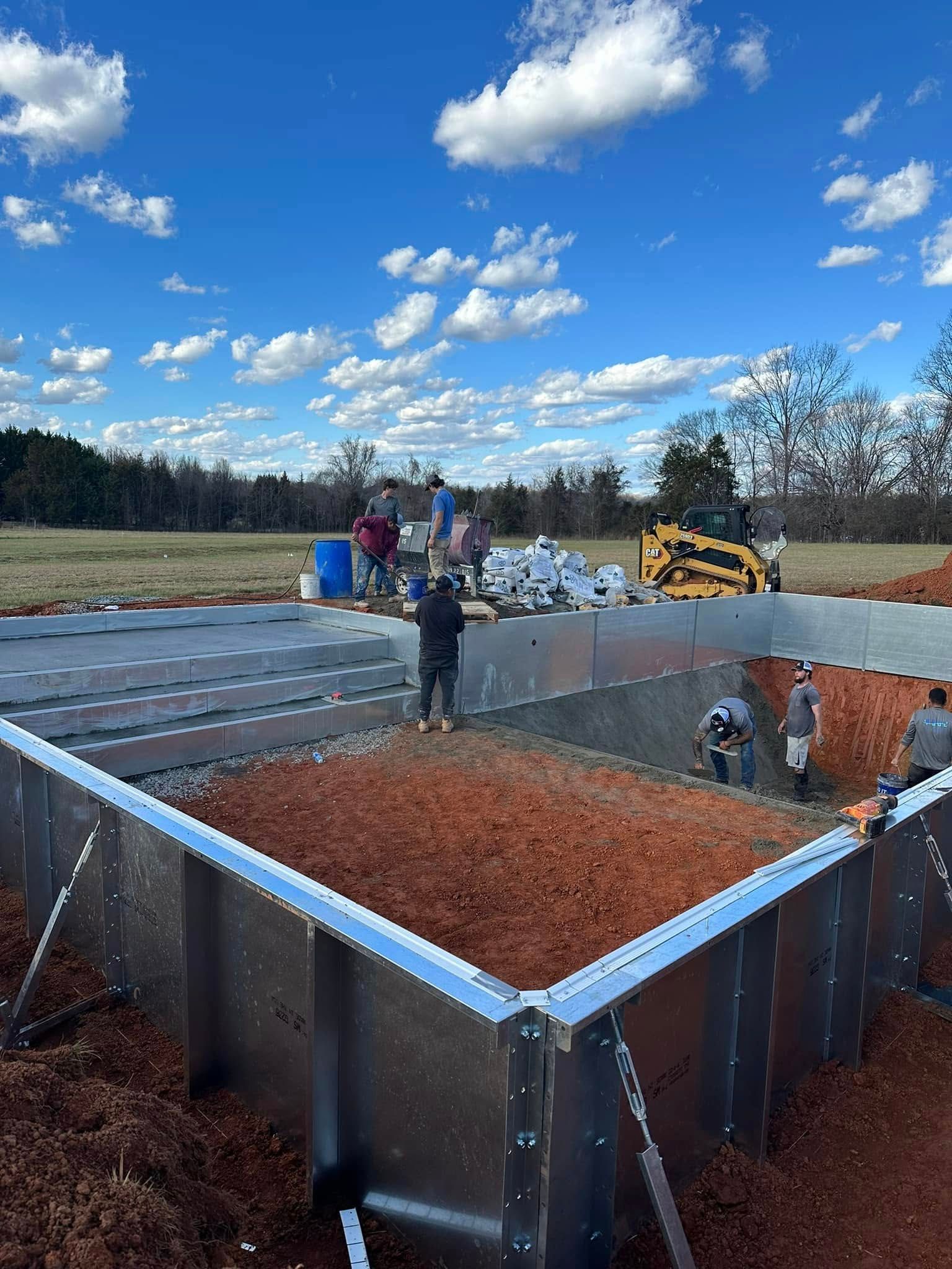 Workers installing a large metal tank outdoors under a blue sky with clouds