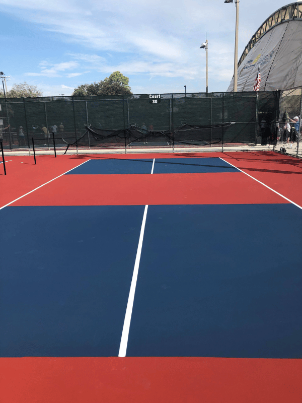 A red and blue tennis court with a fence in the background