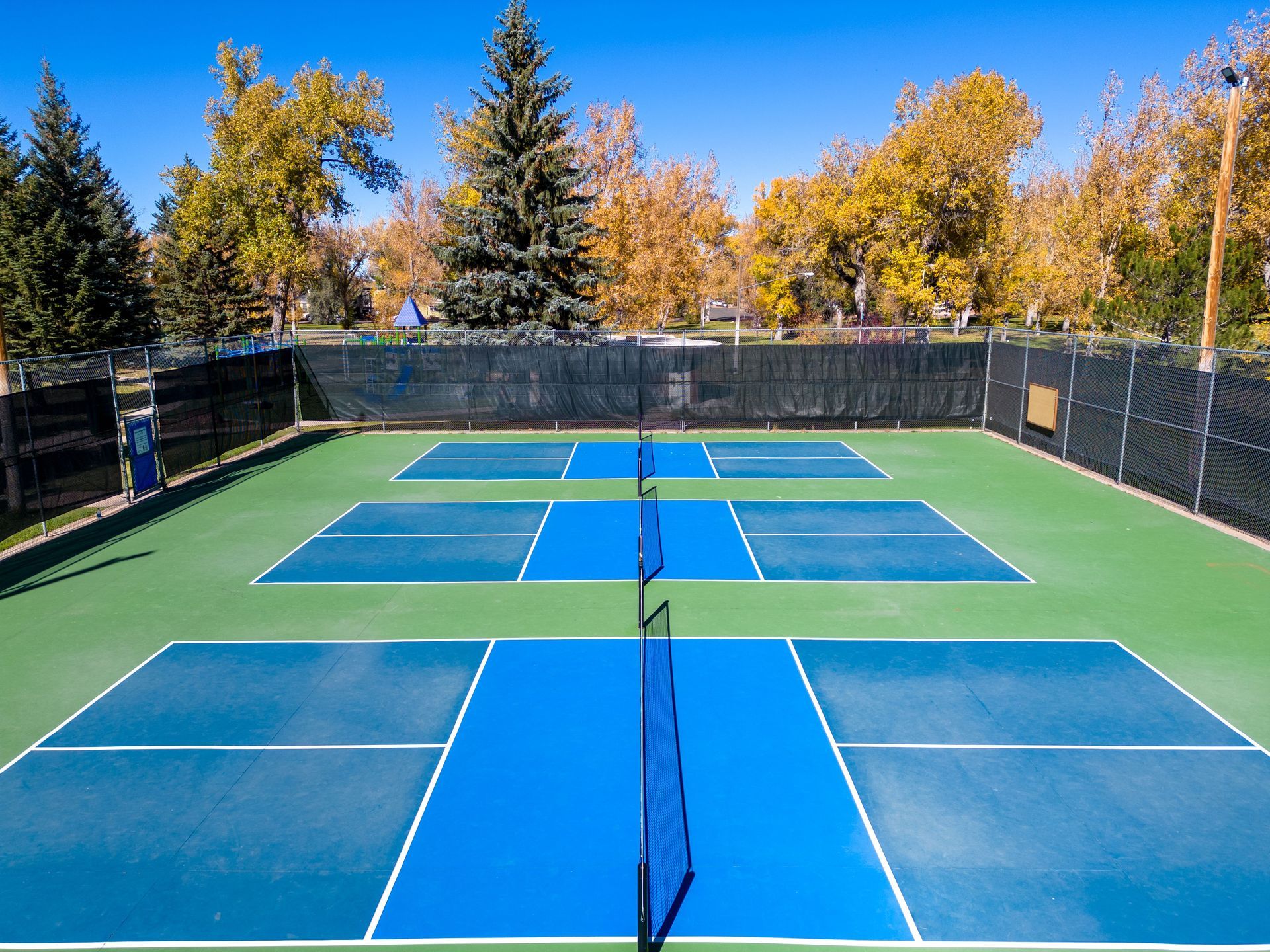An aerial view of a tennis court with trees in the background.