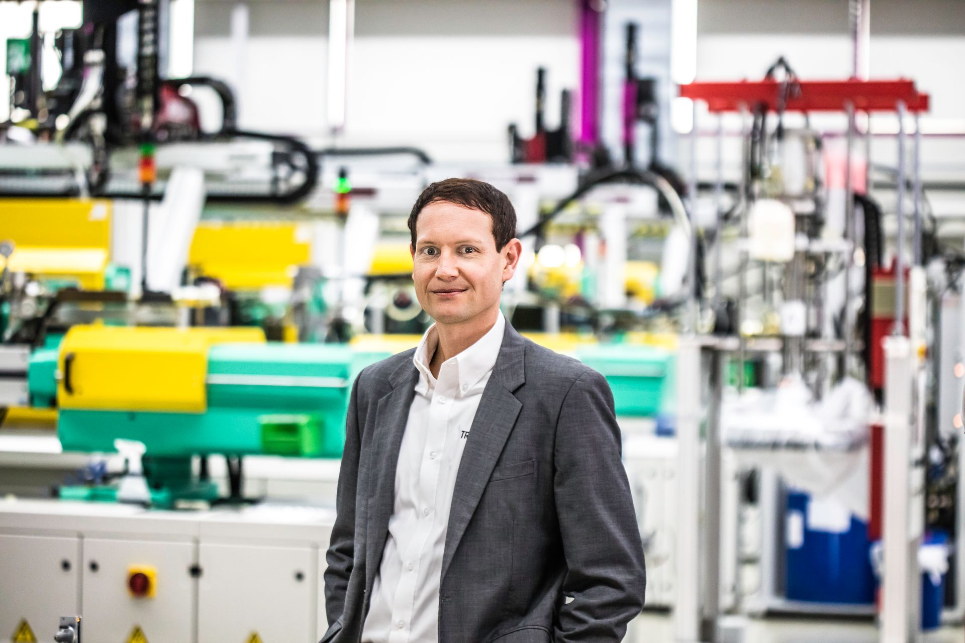 Jarno Burkhardt, General Manager Trelleborg Sealing Solutions, in a suit is standing in front of a machine in a factory.