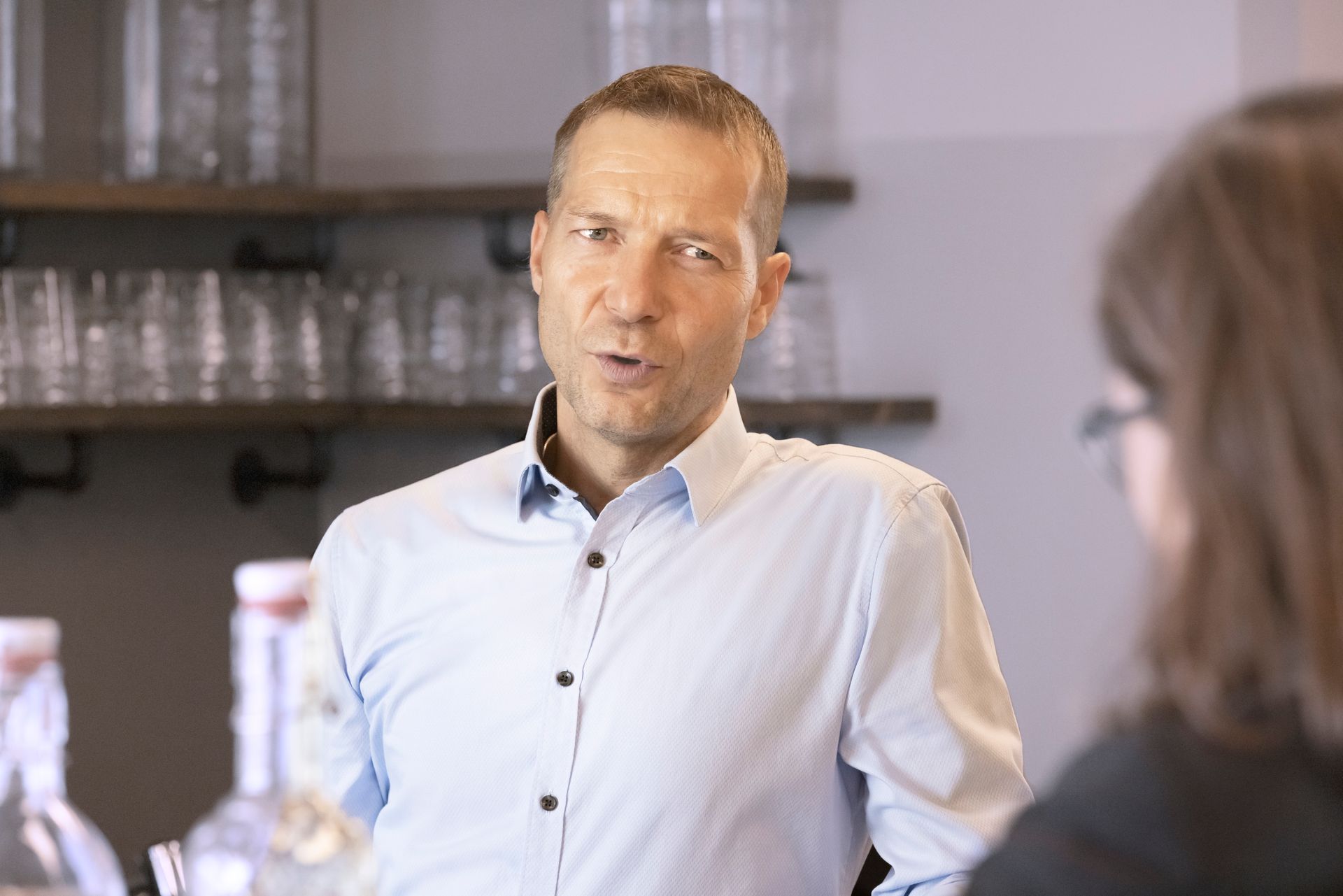Ein Mann in einem blauen Hemd spricht mit einer Frau in einem Büro.