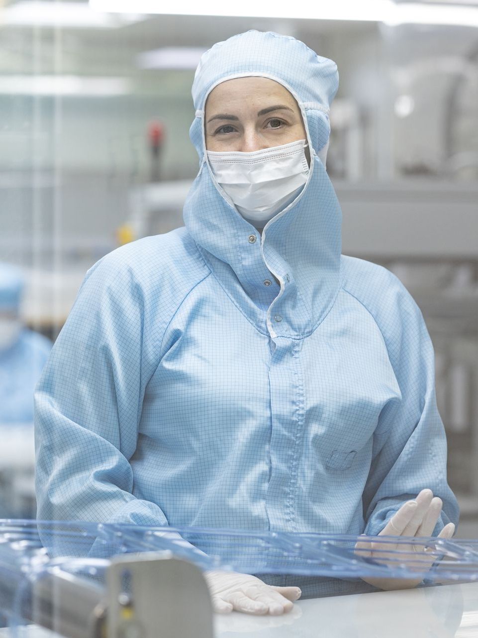 A woman is wearing a protective suit and mask in a clean room.
