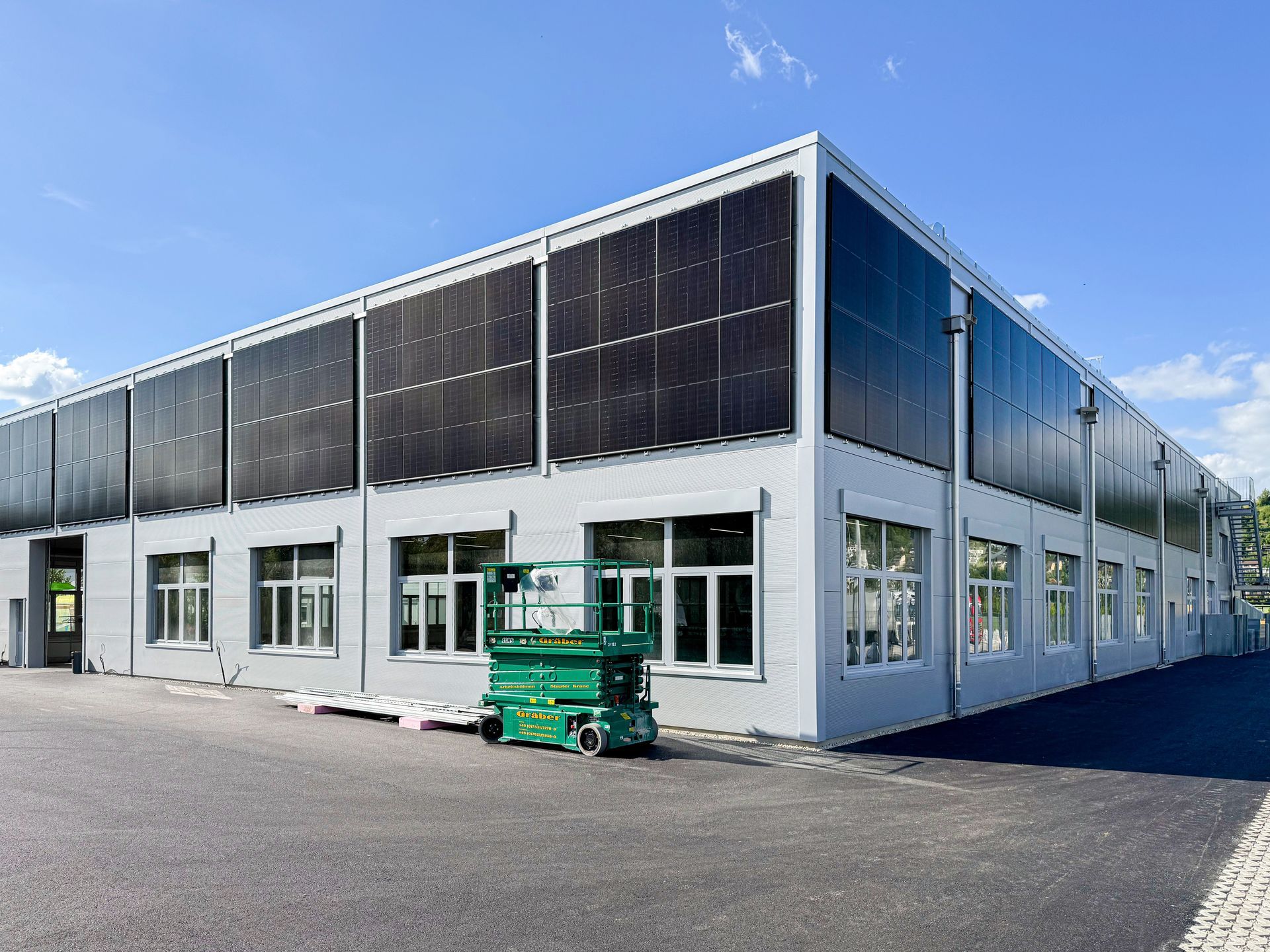 Ein großes Gebäude mit vielen Fenstern und Solarzellen an der Seite.