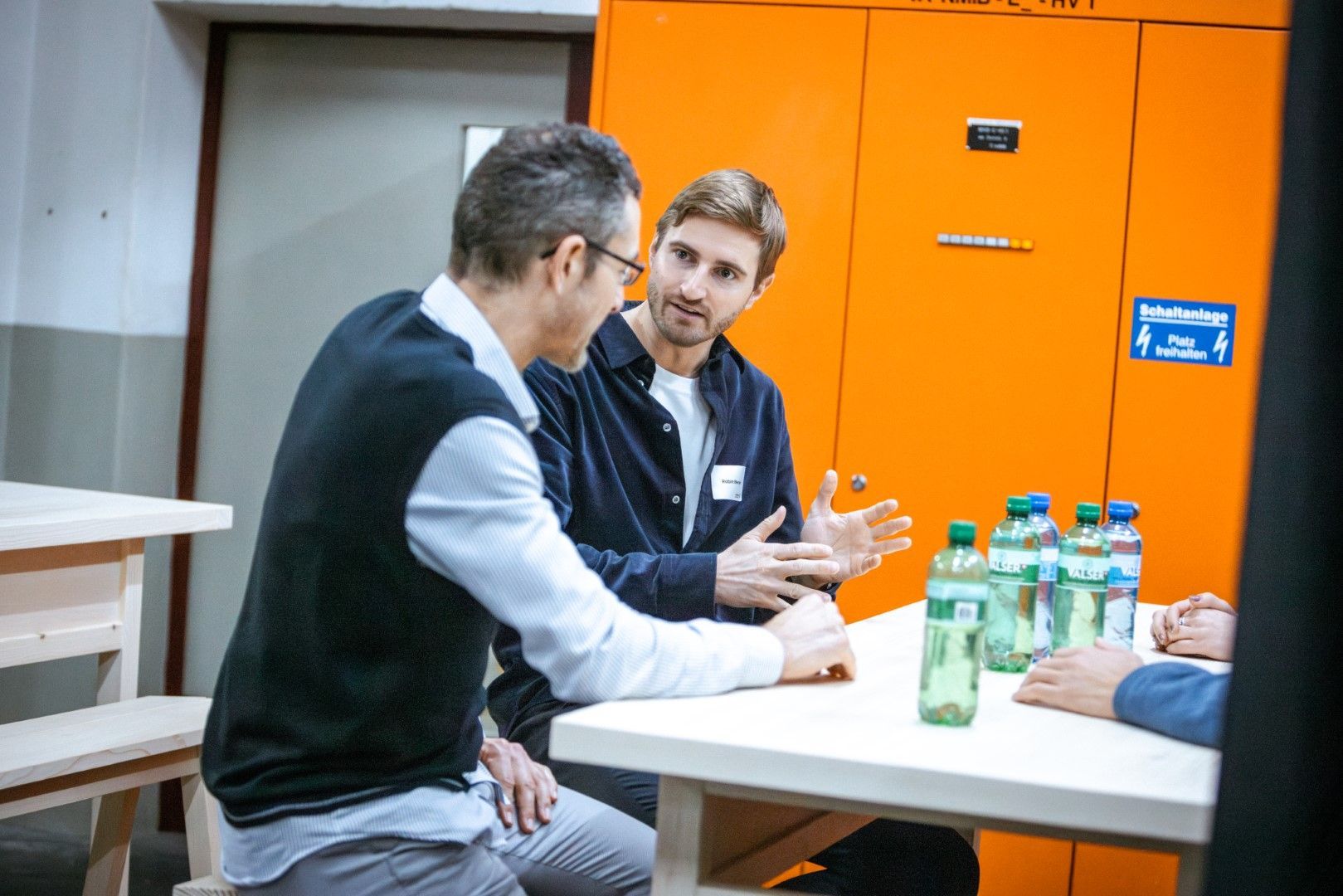 A group of men are sitting at a table talking to each other.