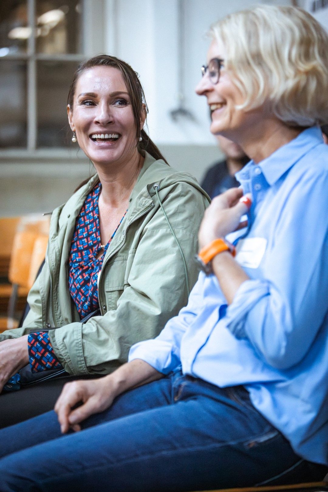 Two women are sitting next to each other and smiling.
