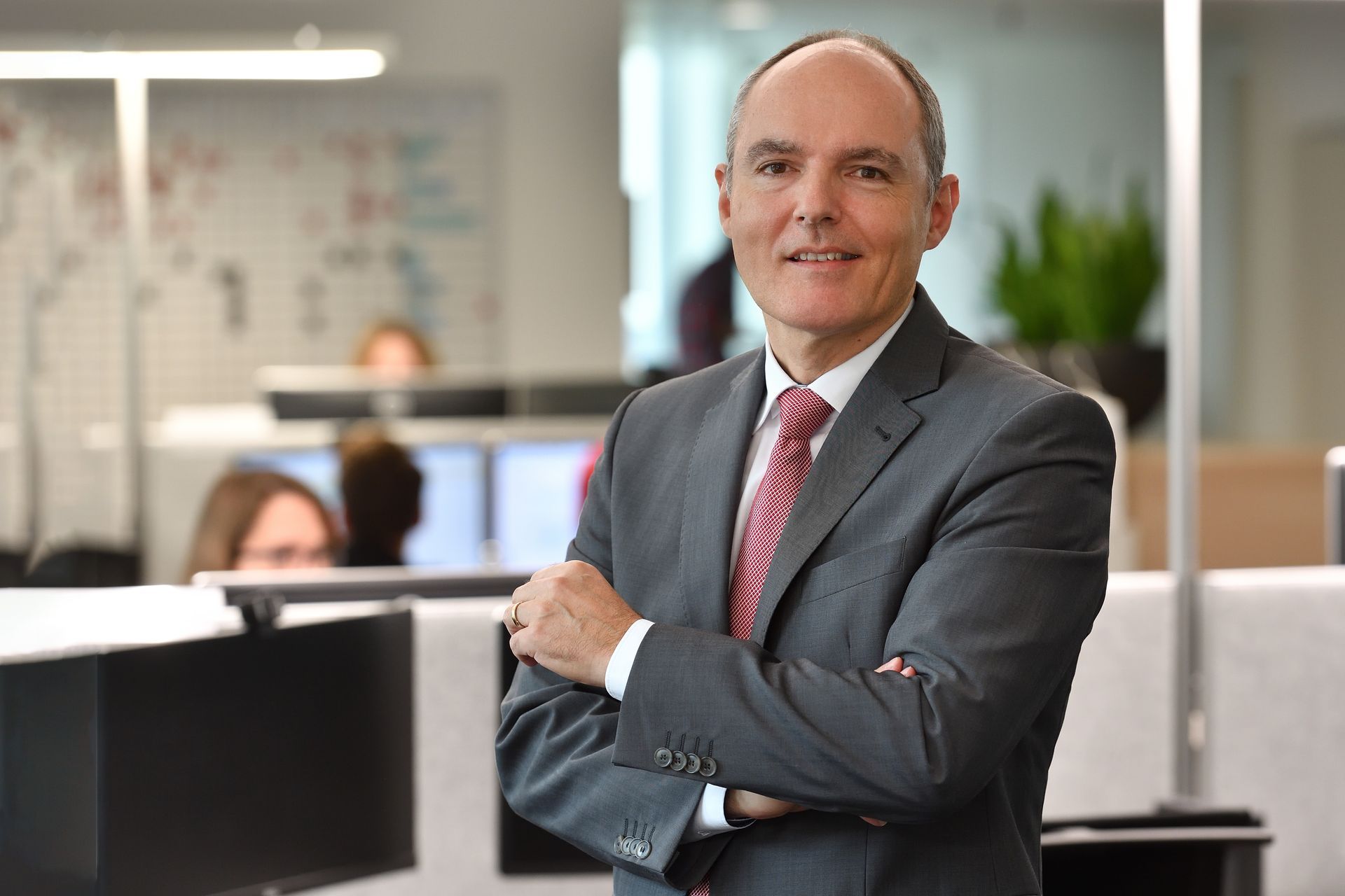 Markus Lickert, Managing Director UBS in a suit and tie is standing in an office with his arms crossed.