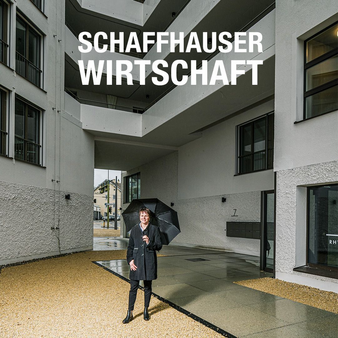 Eine Frau mit Regenschirm vor einem Gebäude mit der Aufschrift „Schaffhauser Wirtschaft“